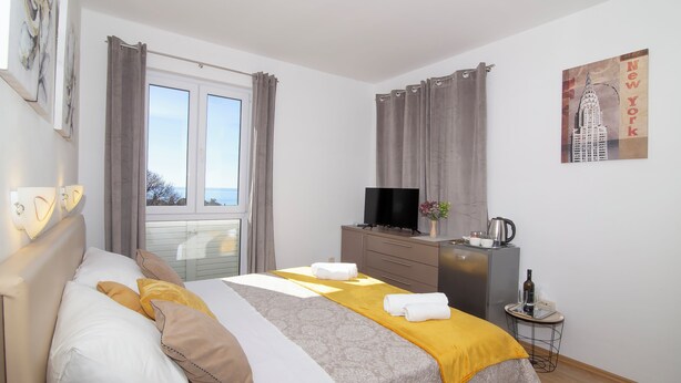 A hotel room with a bed, a TV, a small table with a bottle and glasses, and a painting of the Empire State Building. - Room Beta with sea view (Dubrovnik)