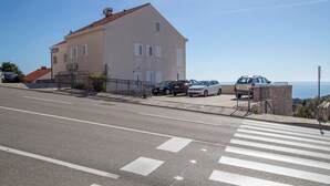 A building with a sloped roof, parked cars, and a pedestrian crossing. - Room Beta with sea view (Dubrovnik)