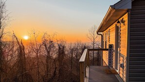 A wooden building with a 'Welcome' sign, a 'Protected' security sign, and a view of the sunset. - Sunrise Mountain Escape - Modern 1 Bed, 1 Bath - Gorgeous Views Near BRPW & I-77 (Fancy Gap)