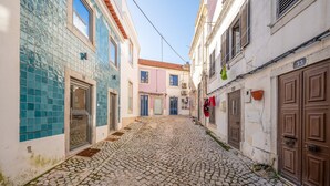 Calle adoquinada entre edificios con fachadas de azulejos y puertas de madera.