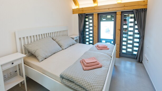 Een slaapkamer met een bed, nachtkastje en een raam met gordijnen.
