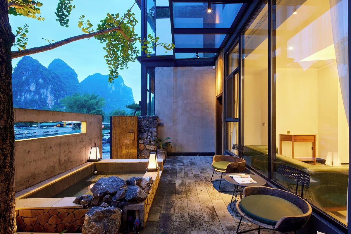 A modern spa area with a stone wall, a hot tub, and seating.