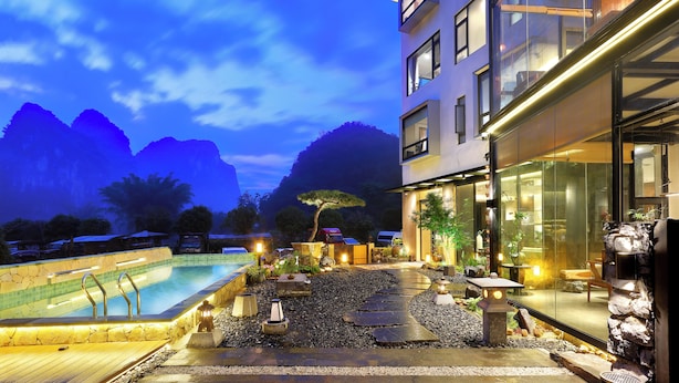 A modern hotel with a swimming pool, stone pathway, and mountain views. - Yangshuo The One Hotel (Guilin)