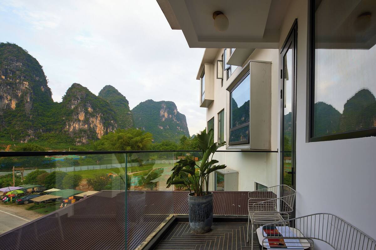 A balcony with a potted plant, a metal chair, and a table.