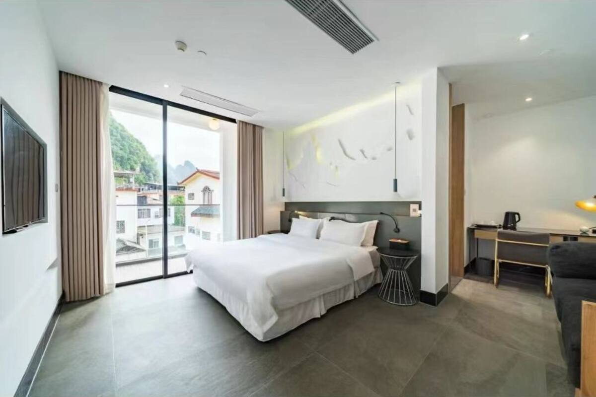 A modern hotel room with a large bed, a desk, and a view of the city.