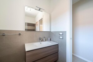 A modern bathroom with a white sink, a mirror, and a towel rack. - Newly Renovated Modern two Room Apartment (San Michele al Tagliamento)