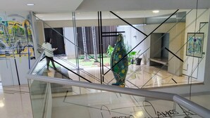 Ein modernes Interieur mit Glastrennwand, einer dekorativen Skulptur und Kunstwerken an den Wänden.
