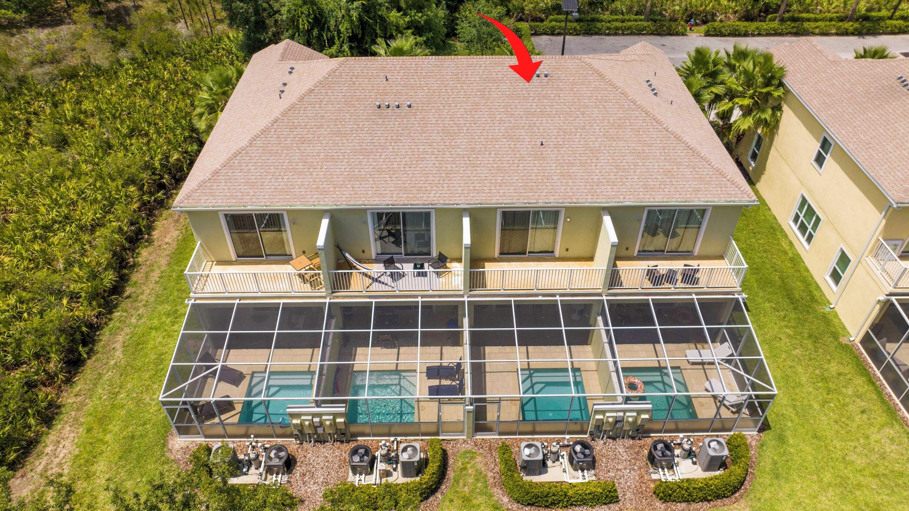 A two-story building with a large balcony, a swimming pool, and a covered outdoor area.