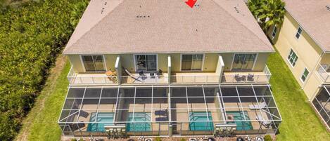 A two-story building with a large balcony, a swimming pool, and a covered outdoor area.