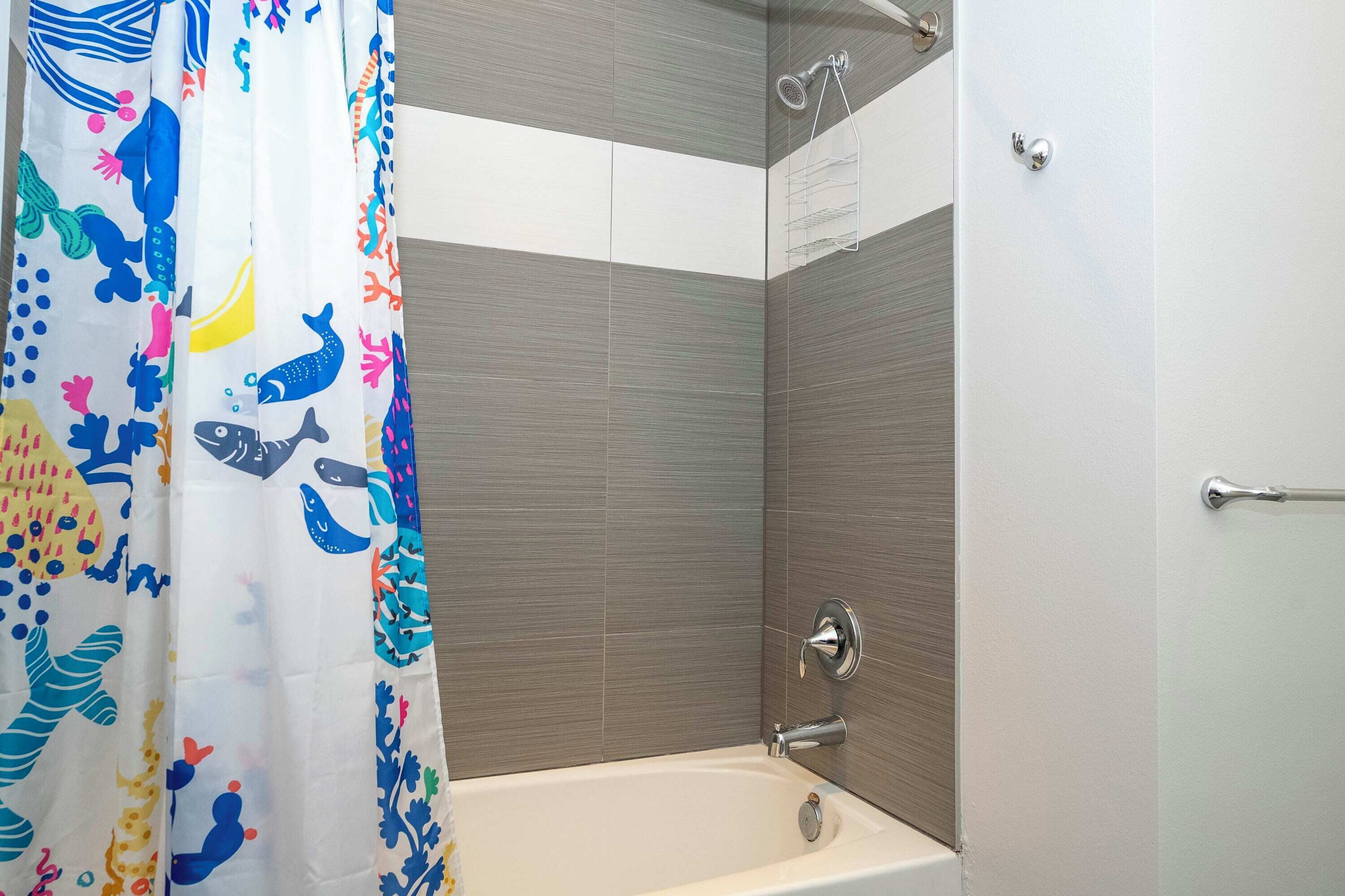 A bathroom with a bathtub, shower, and tiled walls.