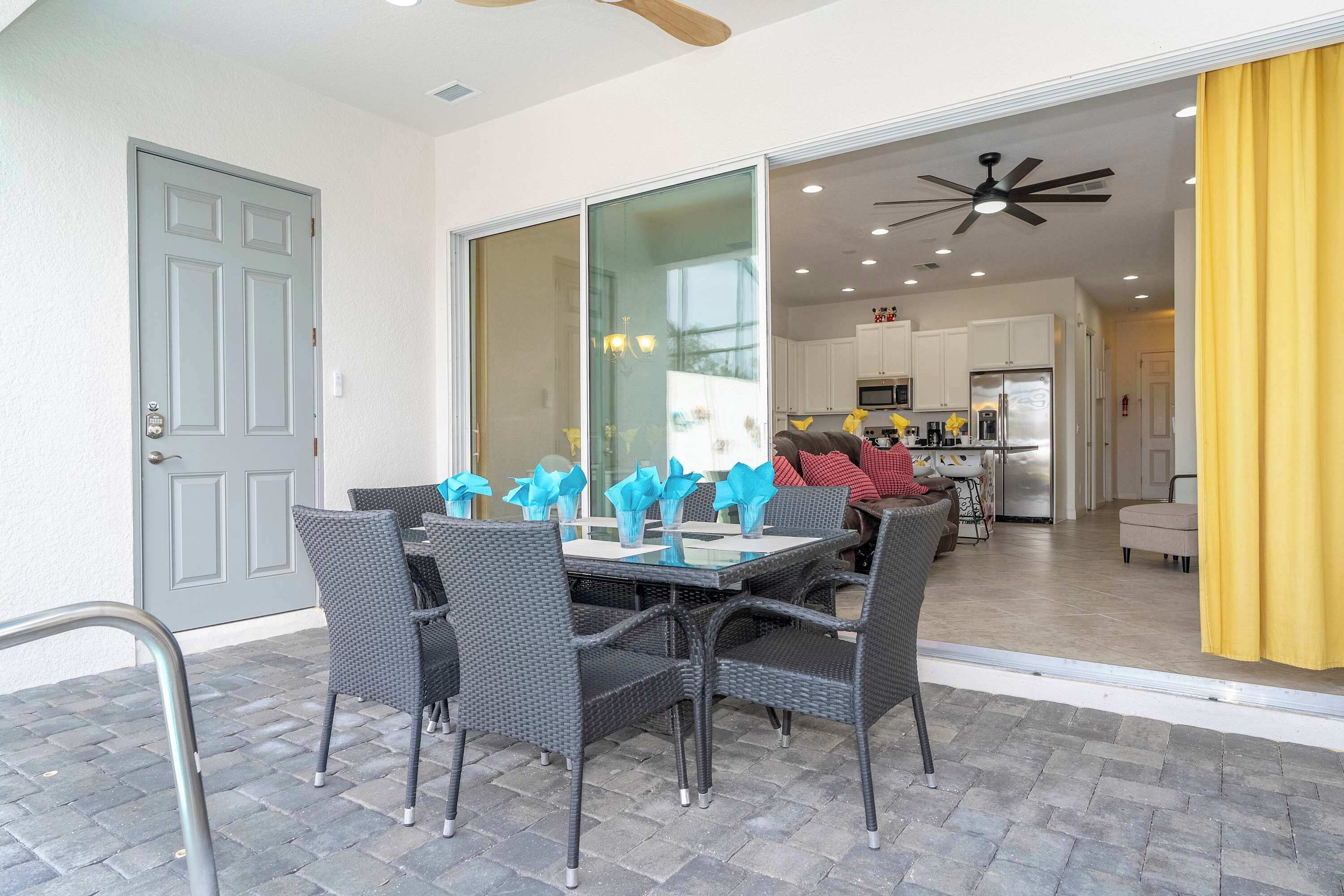 A dining area with a glass partition, black wicker chairs, and a table with blue napkins.