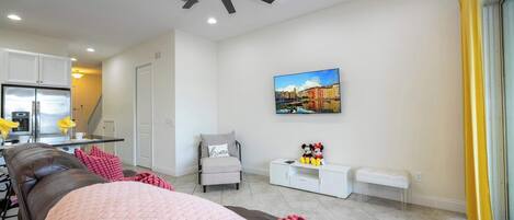 Un soggiorno moderno con ventilatore a soffitto, divano, tavolino da caffè e un quadro appeso al muro.