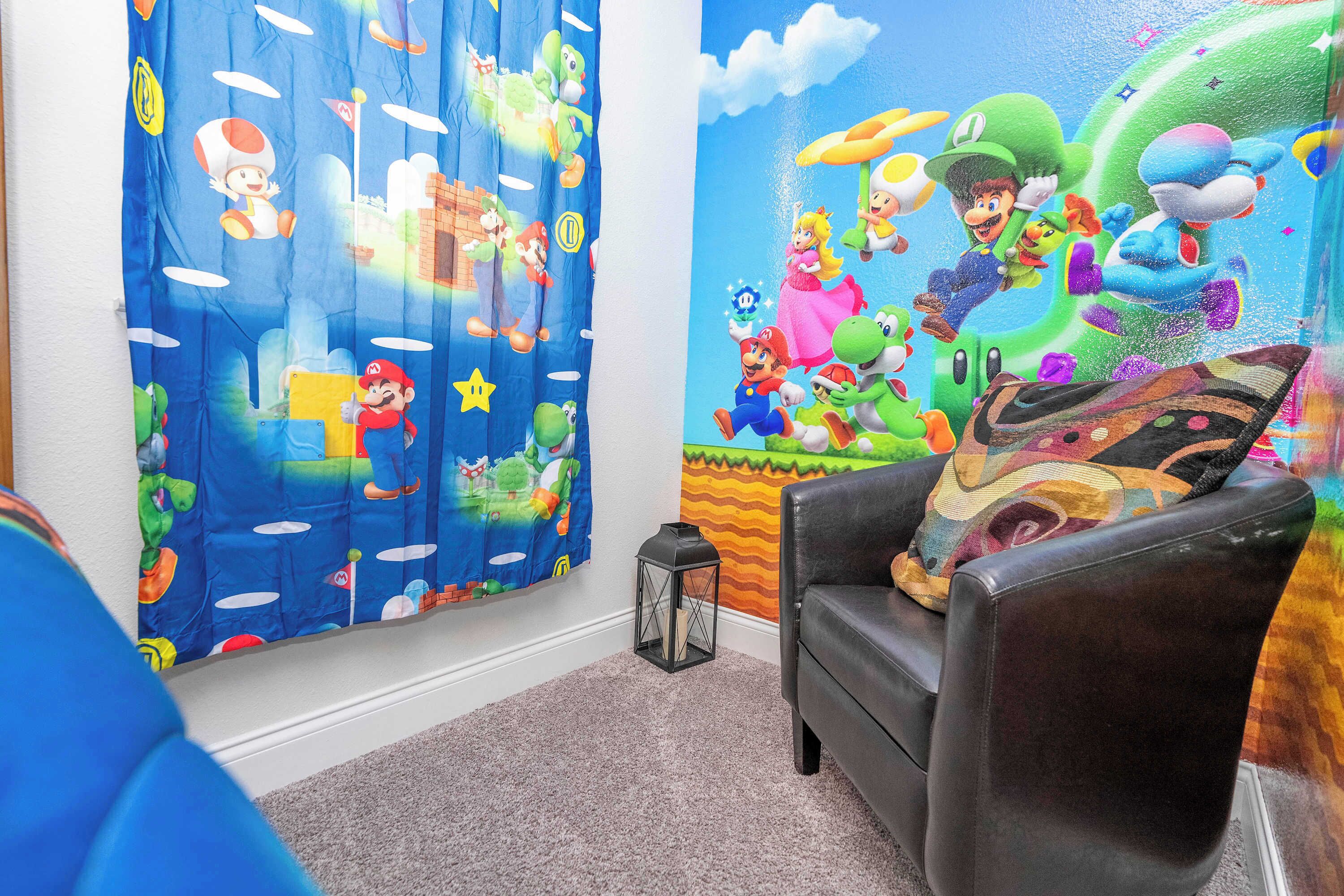 A room with a Nintendo-themed mural, a black leather chair, and a small lantern on the floor.