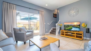 A modern living room with a sofa, coffee table, TV, and a staircase leading to another level. - Cozy 2Bd Spa/Jacuzzi Close To Disney @ Encantada 3029 (Kissimmee)