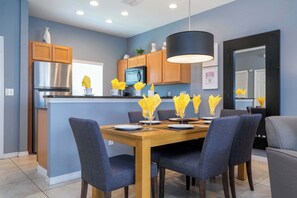 Une cuisine moderne avec des meubles en bois, des appareils en acier inoxydable et un coin repas comprenant une table et des chaises en bois.