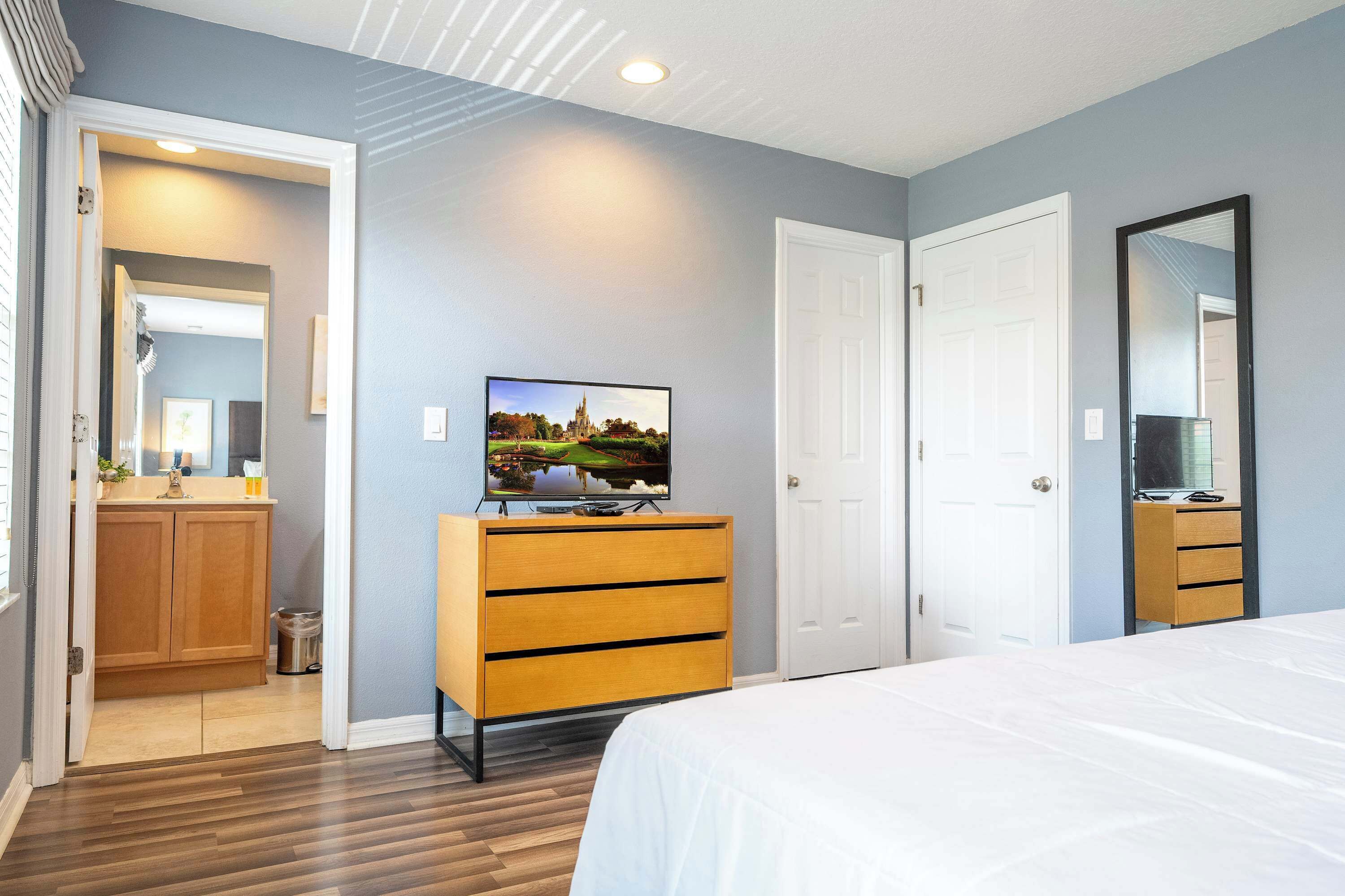A bedroom with a bed, a dresser, a television, and a door.