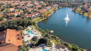 A residential area with a large lake, a fountain, and a swimming pool with lounge chairs. - Cozy 2Bd Spa/Jacuzzi Close To Disney @ Encantada 3029 (Kissimmee)