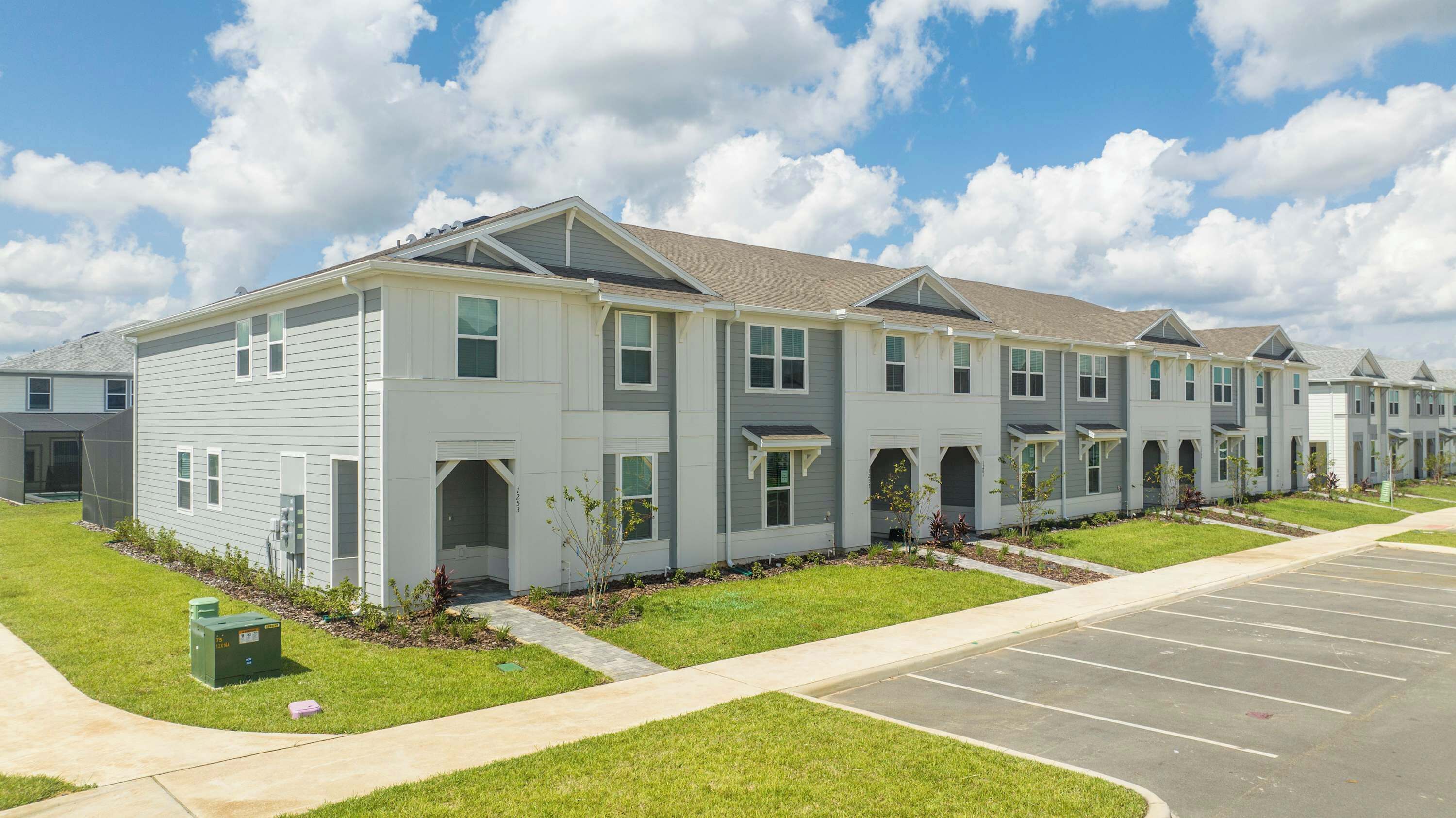 A row of two-story townhouses with a parking lot in front.