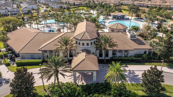 A large resort with multiple swimming pools, palm trees, and a central building with a tiled roof.