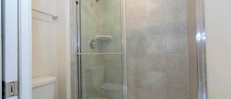 Une salle de bain avec une douche à parois de verre, des toilettes et une baignoire.