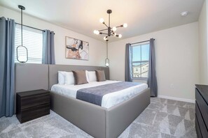 Ein Schlafzimmer mit einem großen Bett, einem Nachttisch, einer Kommode und einer Deckenleuchte.