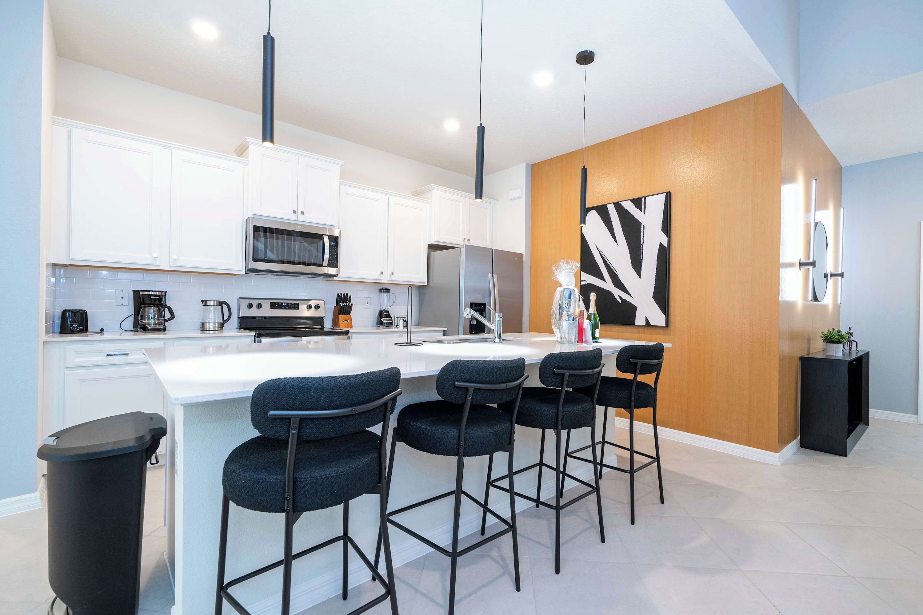 A modern kitchen with white cabinets, stainless steel appliances, and a central island with bar stools.