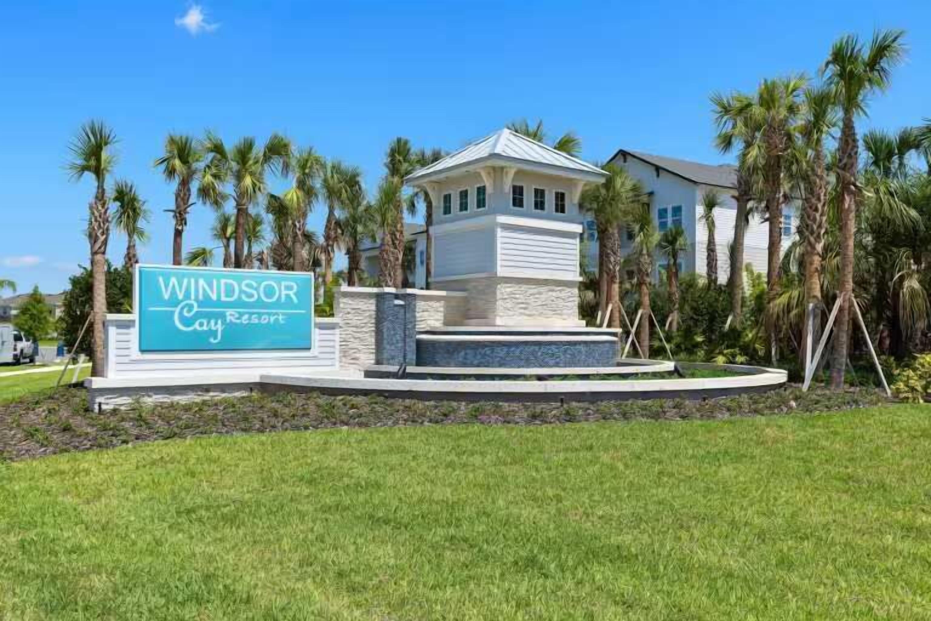 A sign for Windsor Cay Resort with a small building in front, surrounded by palm trees.