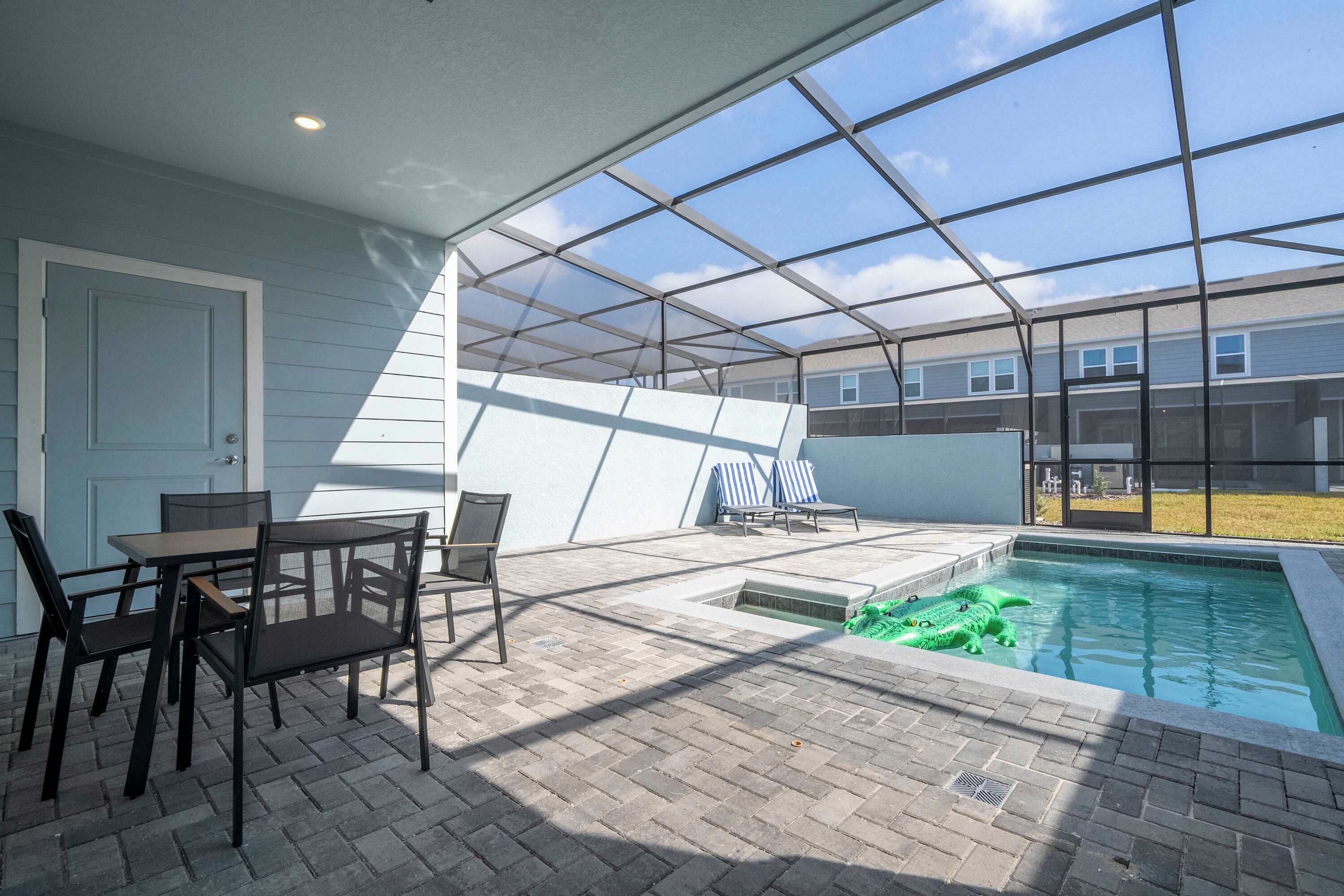 A covered patio area with a pool, outdoor seating, and a view of the neighborhood.