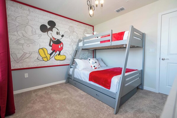 A child's bedroom with a bunk bed, a Mickey Mouse mural, and a red curtain.