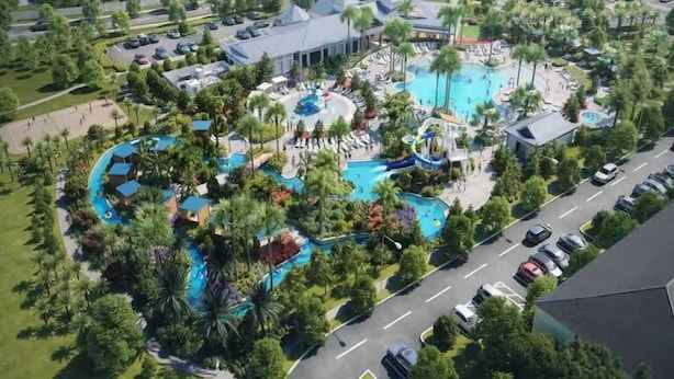 An aerial view of a resort with multiple swimming pools surrounded by palm trees and resort buildings.