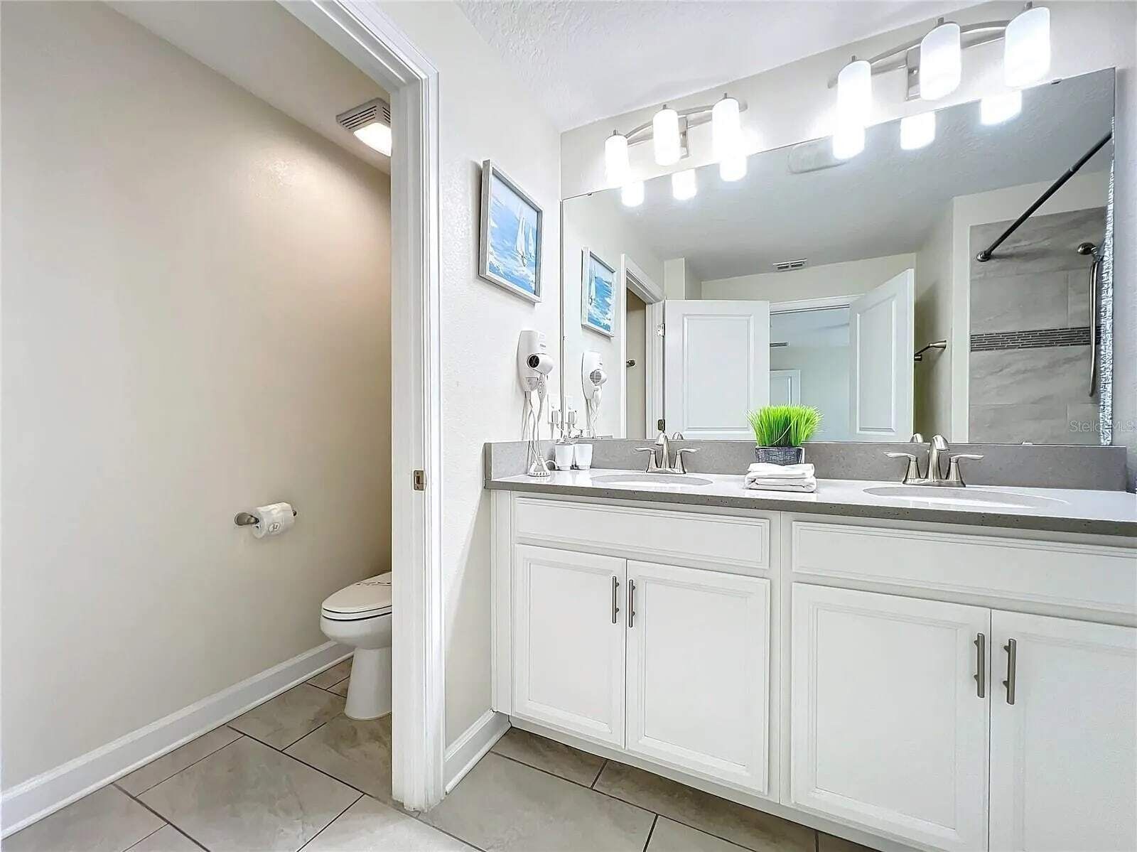Un baño moderno con tocador doble, un espejo grande y una zona de ducha.