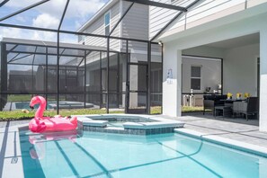 Une piscine avec un flotteur en forme de flamant rose, un patio couvert et une table à manger avec des chaises.