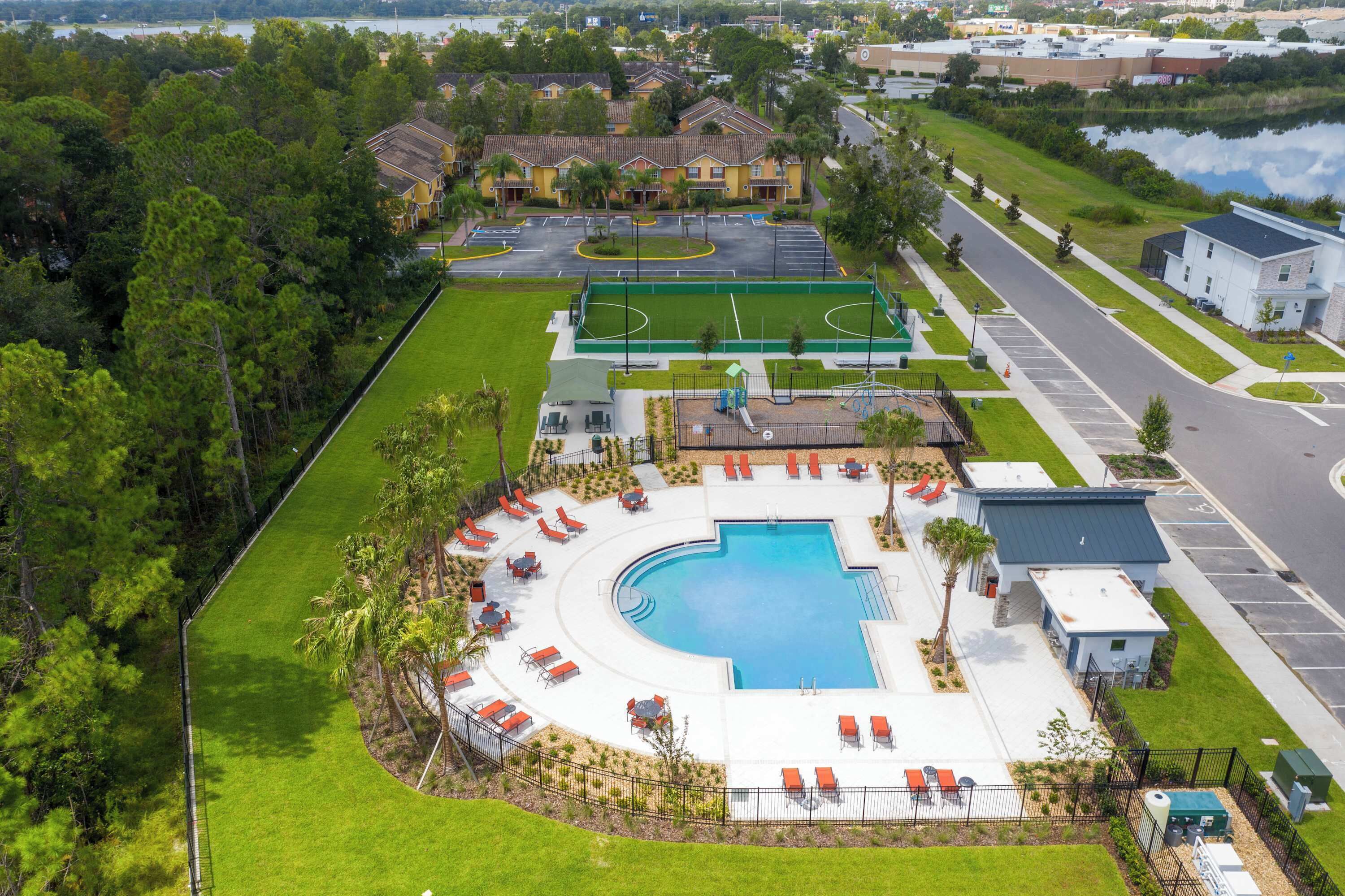 An aerial view of a resort with a swimming pool, tennis courts, and a parking lot.