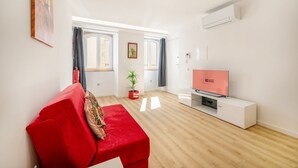 Una sala de estar moderna con un sofá rojo, un televisor de pantalla plana y una planta en maceta.