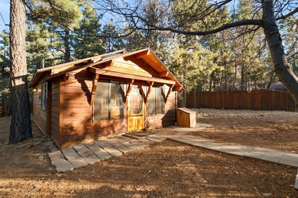 A wooden cabin with a sloped roof, large windows, and a small porch area.
