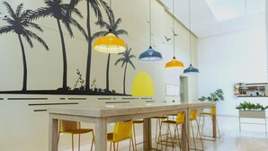 A modern kitchen with a white countertop, yellow chairs, and hanging pendant lights. - Exclusive Apartment Seaview - Samaria Club Playa (Gaira)