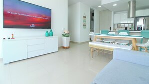 A modern living room with a flat-screen TV, a dining area with a table and chairs, and a kitchen with cabinets and a stove. - Exclusive Apartment Seaview - Samaria Club Playa (Gaira)