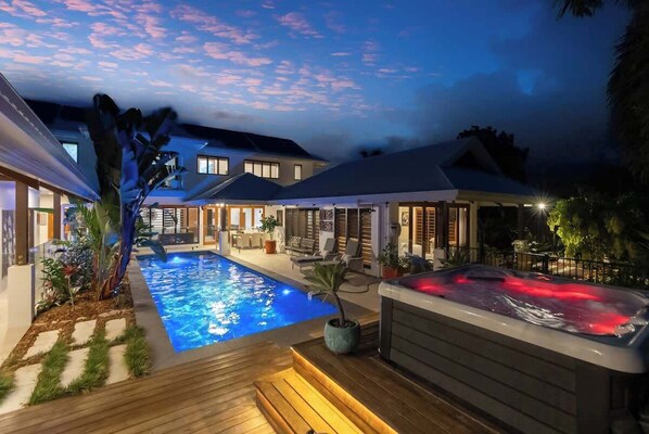 A swimming pool with a hot tub, outdoor seating, and a covered patio area.