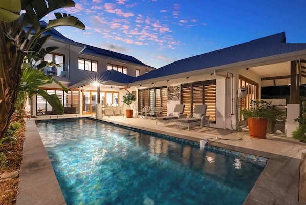 A modern house with a swimming pool, outdoor seating, and large windows.