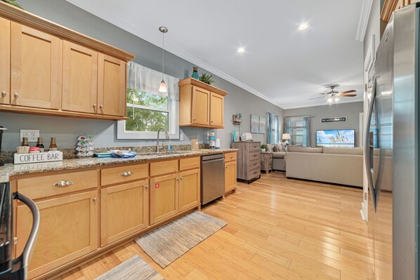 Enjoy cooking in this well-equipped kitchen with a dishwasher and coffee bar, adjacent to a cozy living area with a sofa and flat-screen TV.