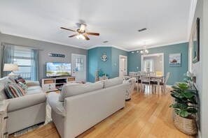 Relax in this stylish living room with a large sofa, flat-screen TV, and dining area.
