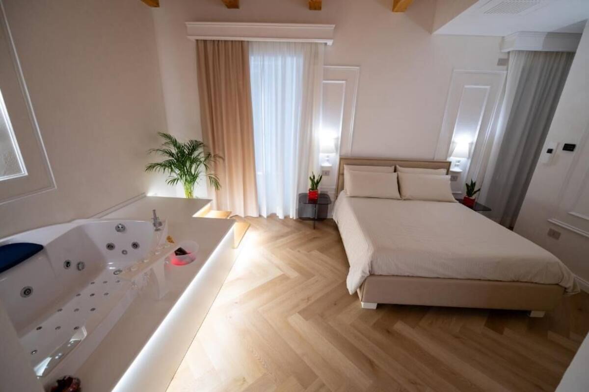 Quarto com cama grande, banheira e planta em vaso.