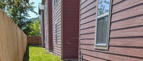 Un barrio residencial con un césped cuidado, valla de madera y casas con revestimiento rojo.
