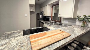 Eine moderne Küche mit Granit-Arbeitsplatten, einem Einbauherd und weißen Schränken.
