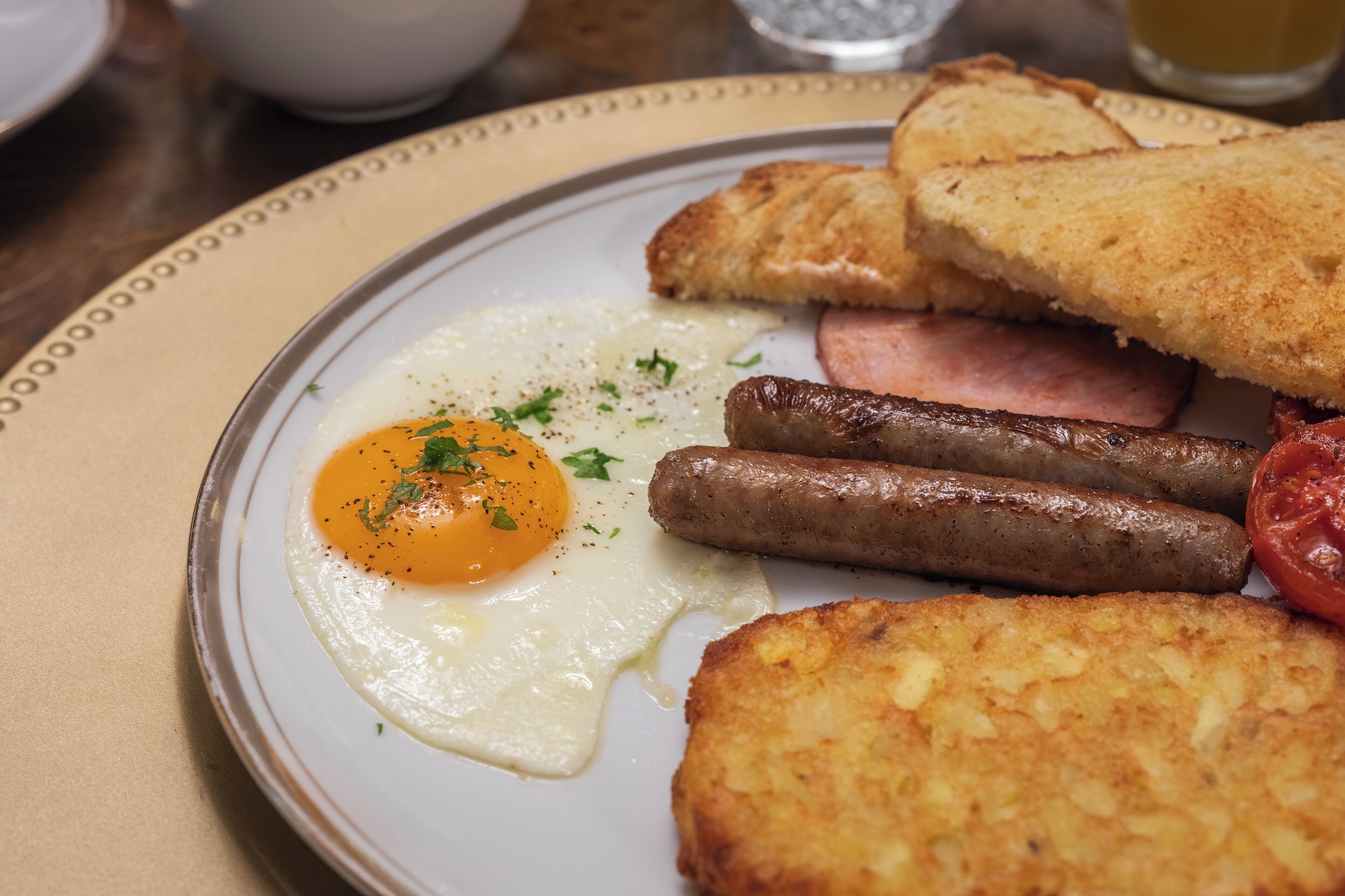 Un plato de comida para el desayuno con huevos, salchichas y tostadas.