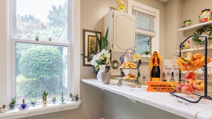 A kitchen with a window, potted plants, a fruit basket, and a sign. - The Clayton Magnolia Inn (Clayton)