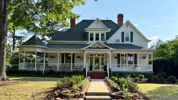 A two-story house with a porch, a covered front entrance, and a number '507' on the steps. - The Clayton Magnolia Inn (Clayton)