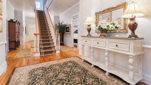 A staircase with wooden steps and a carpeted floor, leading to a landing with a white console table and a mirror. - The Clayton Magnolia Inn (Clayton)