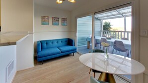 Una sala de estar moderna con un sofá azul, una mesa de comedor redonda y una lámpara en el techo.
