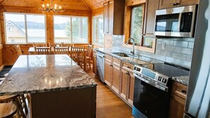 Una cocina moderna con armarios de madera, encimeras de granito, electrodomésticos de acero inoxidable y una isla grande con asientos.